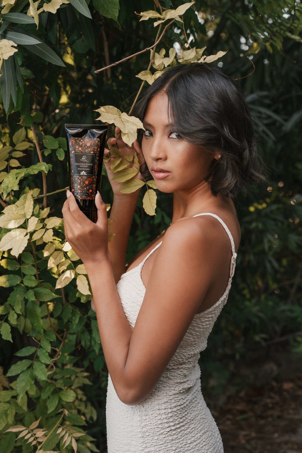 Modella beauty con crema cosmetica tra le foglie